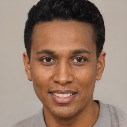 Joyful black young-adult male with short  black hair and brown eyes