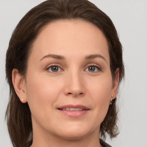 Joyful white young-adult female with medium  brown hair and green eyes