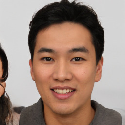 Joyful asian young-adult male with short  black hair and brown eyes