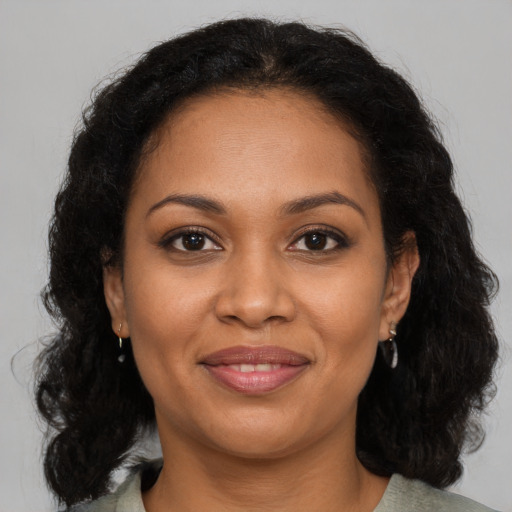 Joyful black young-adult female with long  brown hair and brown eyes