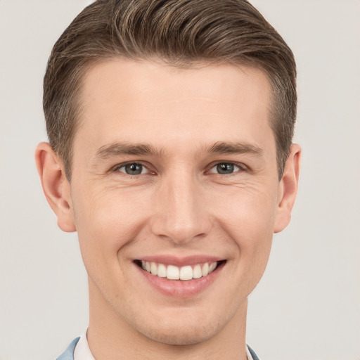 Joyful white young-adult male with short  brown hair and grey eyes