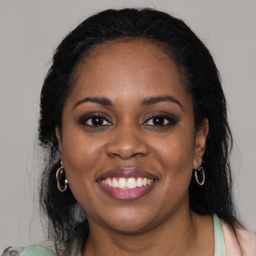 Joyful black young-adult female with long  black hair and brown eyes