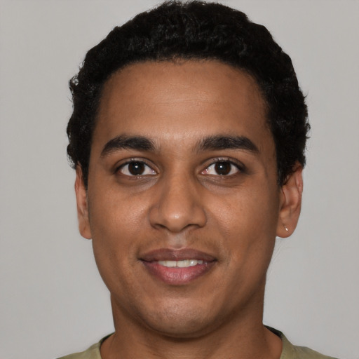 Joyful black young-adult male with short  black hair and brown eyes