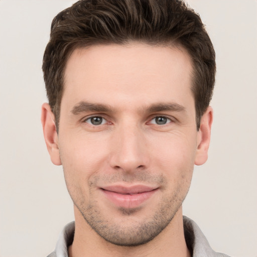 Joyful white young-adult male with short  brown hair and grey eyes