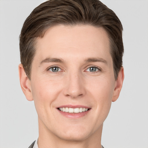 Joyful white young-adult male with short  brown hair and grey eyes