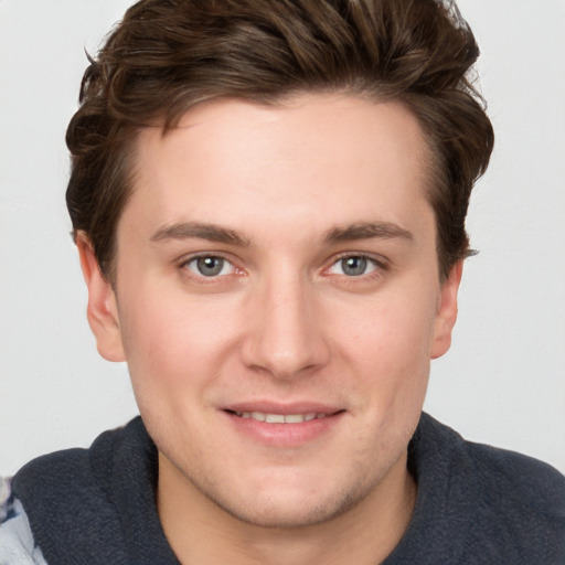 Joyful white young-adult male with short  brown hair and blue eyes