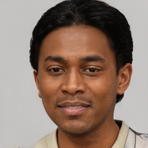 Joyful black young-adult male with short  black hair and brown eyes