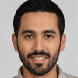 Joyful latino young-adult male with short  black hair and brown eyes