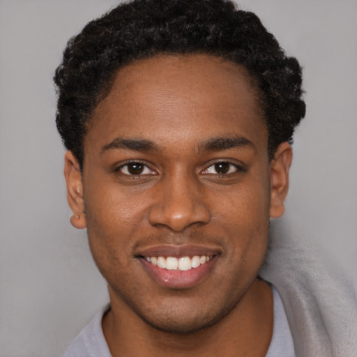 Joyful black young-adult male with short  brown hair and brown eyes