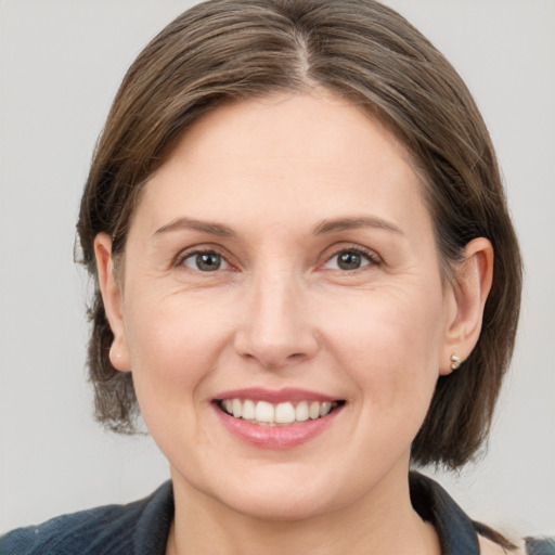 Joyful white adult female with medium  brown hair and grey eyes