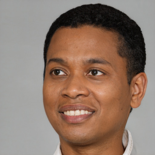 Joyful black young-adult male with short  black hair and brown eyes