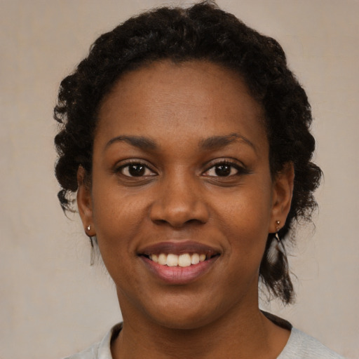 Joyful black young-adult female with short  black hair and brown eyes