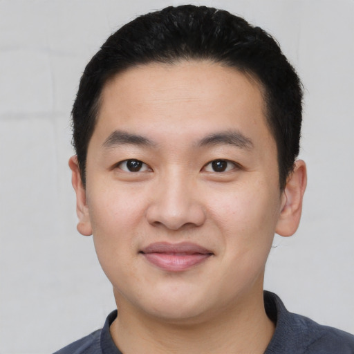 Joyful asian young-adult male with short  black hair and brown eyes