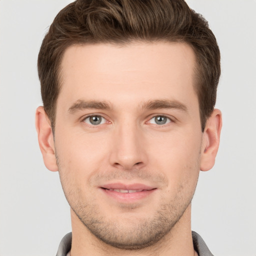 Joyful white young-adult male with short  brown hair and grey eyes