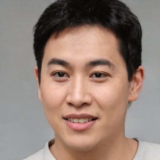 Joyful asian young-adult male with short  brown hair and brown eyes