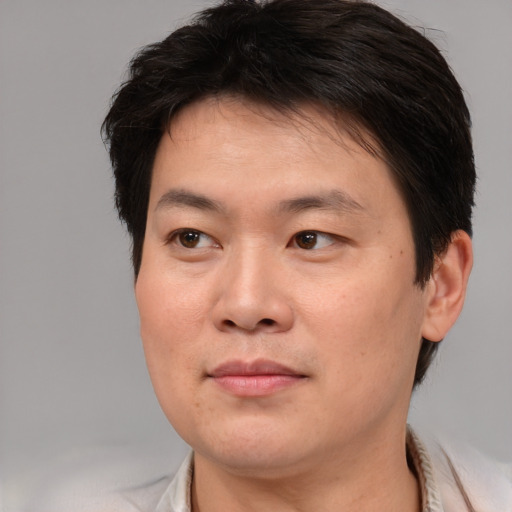 Joyful asian adult male with short  brown hair and brown eyes