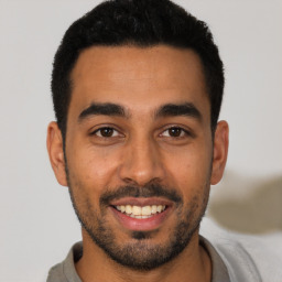 Joyful latino young-adult male with short  black hair and brown eyes