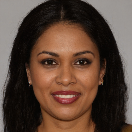 Joyful black young-adult female with long  brown hair and brown eyes