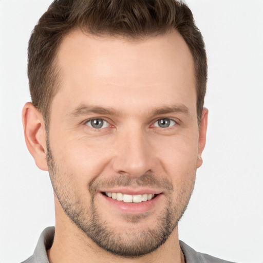 Joyful white young-adult male with short  brown hair and grey eyes