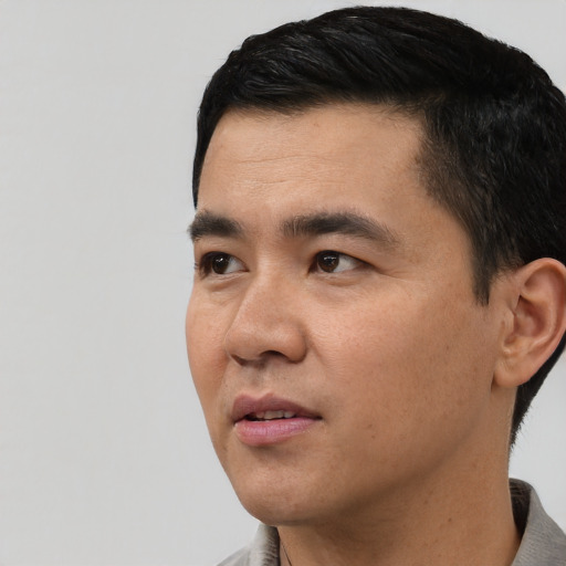 Joyful asian young-adult male with short  black hair and brown eyes