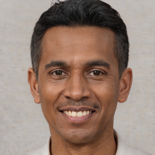 Joyful latino adult male with short  black hair and brown eyes