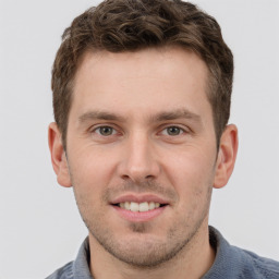 Joyful white young-adult male with short  brown hair and grey eyes