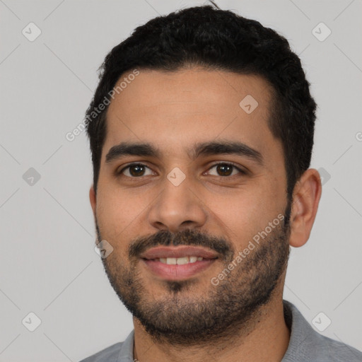 Joyful latino young-adult male with short  black hair and brown eyes