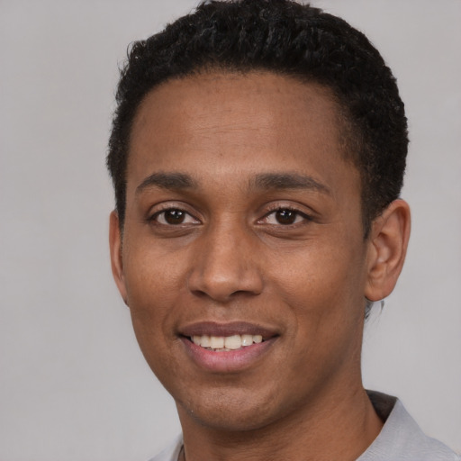 Joyful black young-adult male with short  black hair and brown eyes