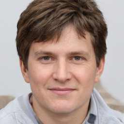 Joyful white young-adult male with short  brown hair and grey eyes