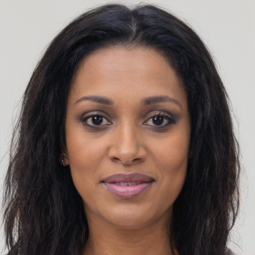 Joyful black young-adult female with long  brown hair and brown eyes