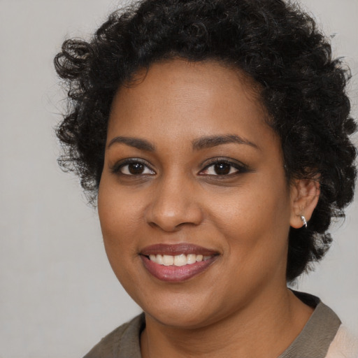 Joyful black young-adult female with long  brown hair and brown eyes