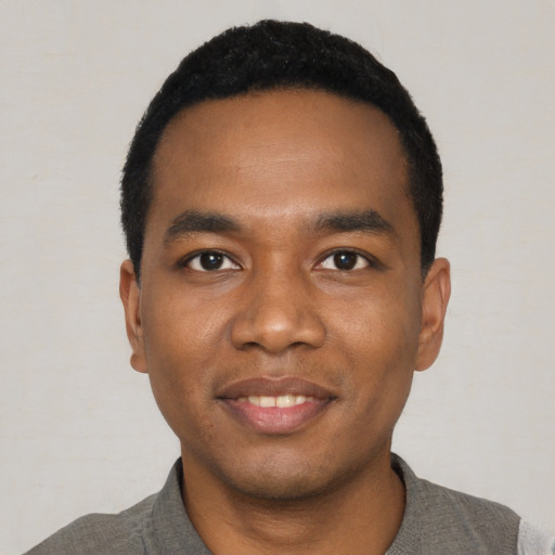 Joyful black young-adult male with short  black hair and brown eyes