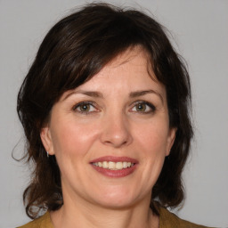 Joyful white adult female with medium  brown hair and green eyes