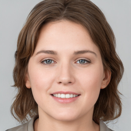 Joyful white young-adult female with medium  brown hair and grey eyes