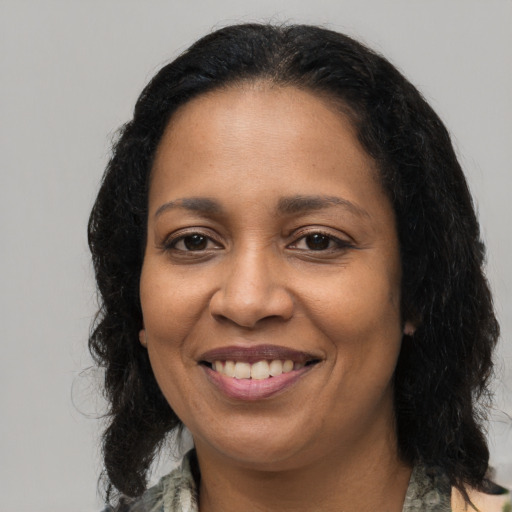 Joyful black adult female with long  brown hair and brown eyes