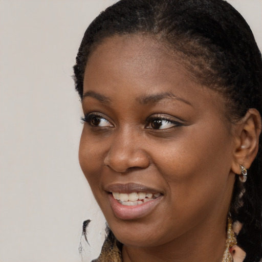 Joyful black young-adult female with long  brown hair and brown eyes