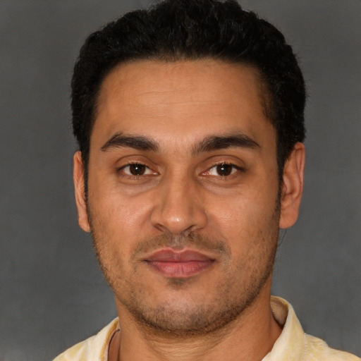 Joyful latino young-adult male with short  black hair and brown eyes