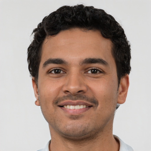 Joyful latino young-adult male with short  black hair and brown eyes