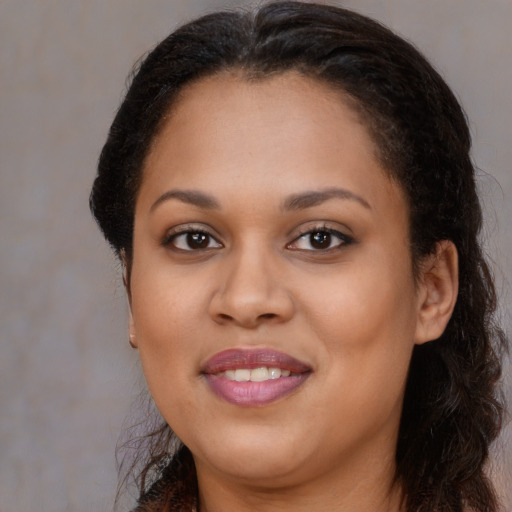 Joyful black young-adult female with long  brown hair and brown eyes