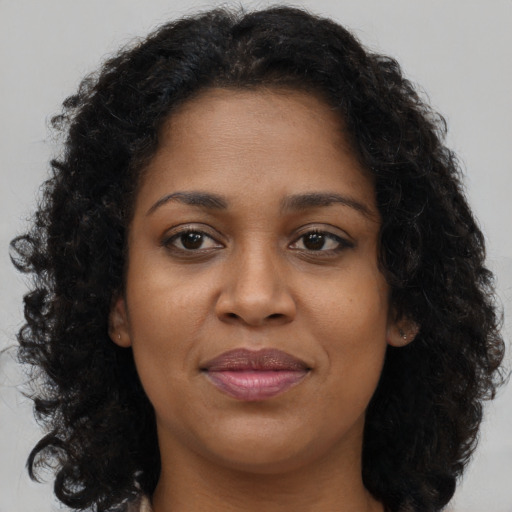 Joyful black young-adult female with long  brown hair and brown eyes
