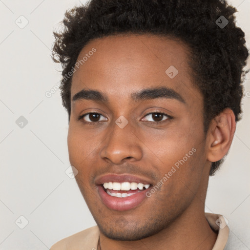 Joyful black young-adult male with short  brown hair and brown eyes