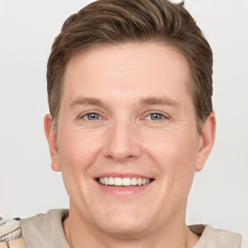 Joyful white young-adult male with short  brown hair and grey eyes