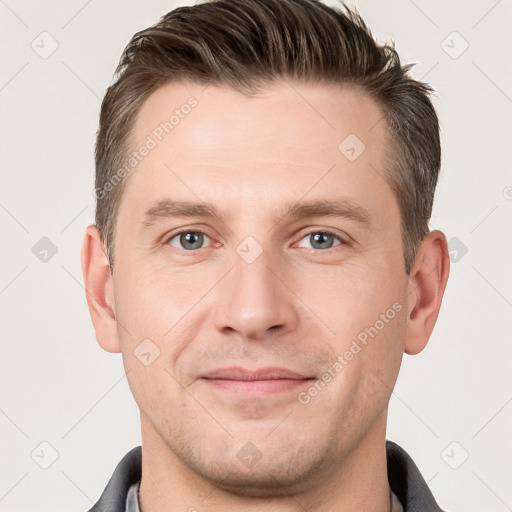 Joyful white young-adult male with short  brown hair and grey eyes