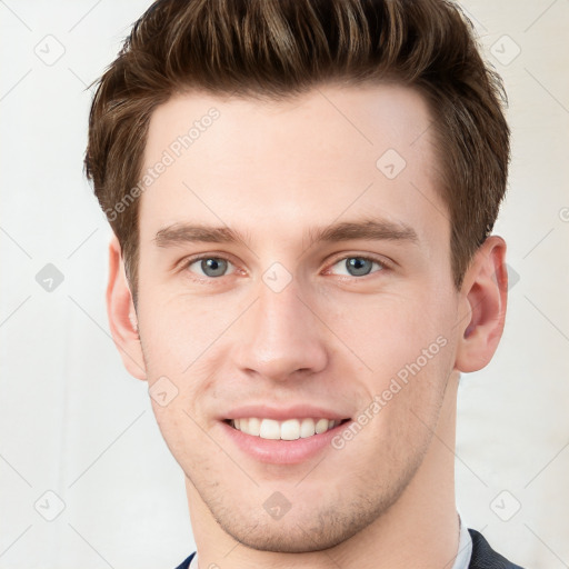 Joyful white young-adult male with short  brown hair and grey eyes