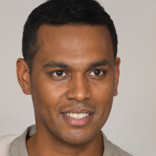 Joyful black young-adult male with short  brown hair and brown eyes