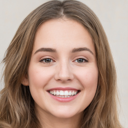 Joyful white young-adult female with long  brown hair and green eyes