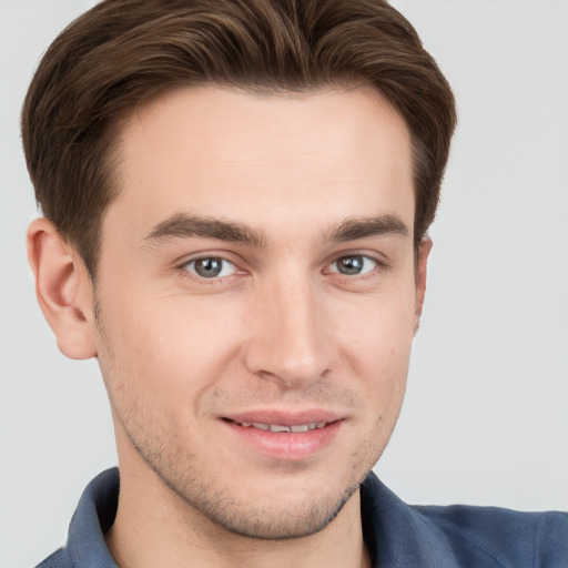 Joyful white young-adult male with short  brown hair and grey eyes