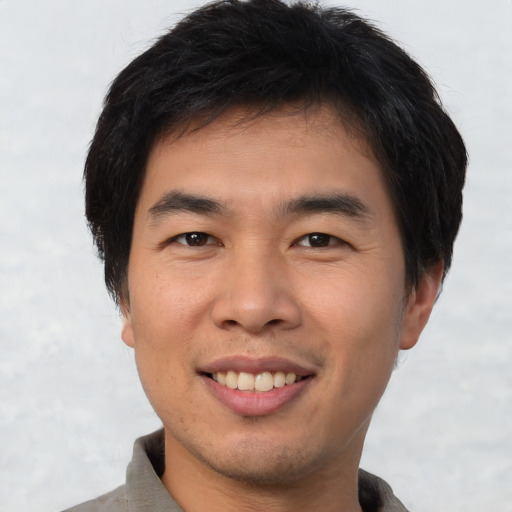 Joyful asian young-adult male with short  brown hair and brown eyes