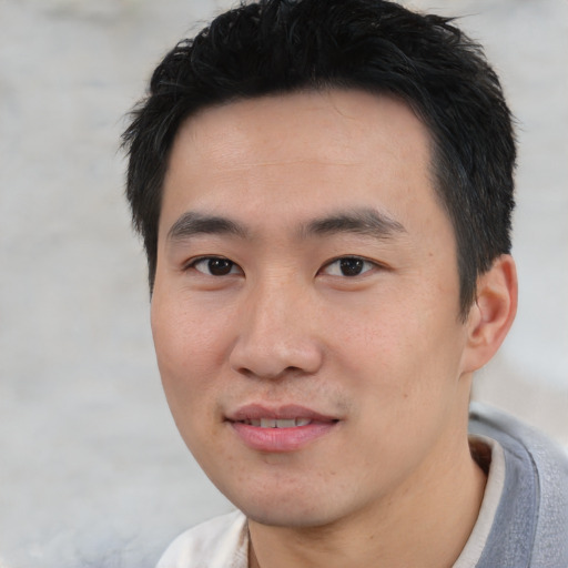 Joyful asian young-adult male with short  black hair and brown eyes