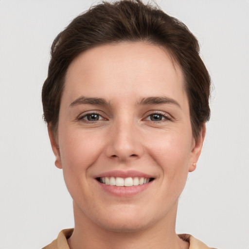 Joyful white young-adult female with short  brown hair and grey eyes